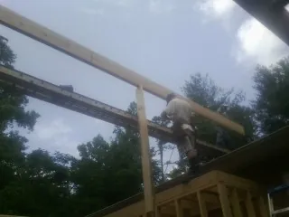 Carpenter setting a ridge beam over a new addition frame — Ice Dam Removal by Roofing Brothers in Springport